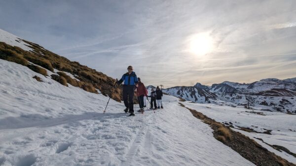 Participantes caminando sobre la nieve en una ruta de raquetas de nieve en Astún