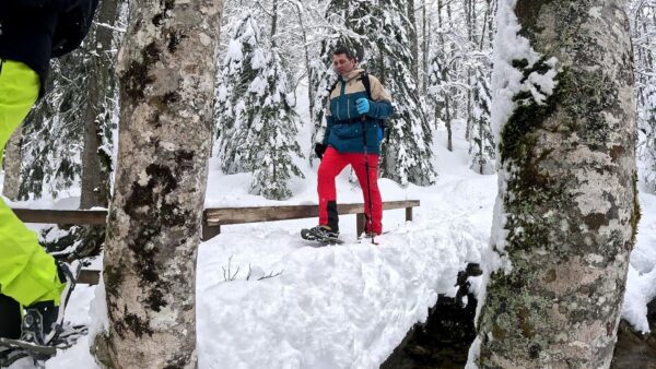 Participante camina con sus raquetas de nieve a través de un bosque nevado